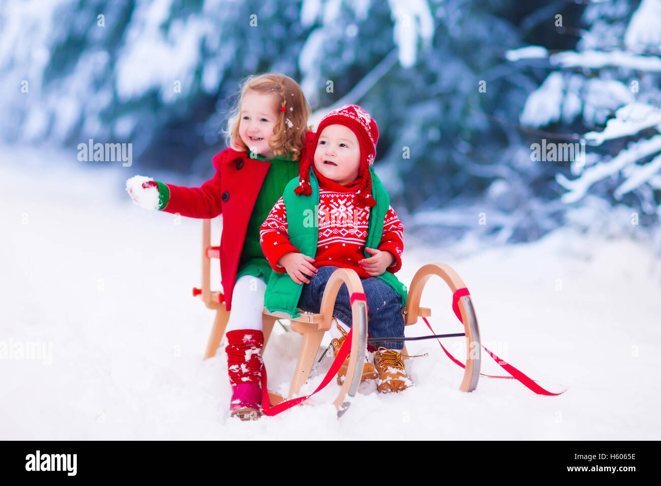 Infant Sleigh Riding Little girl and boy enjoy a sleigh ride. Child sledding. Toddler kid ...