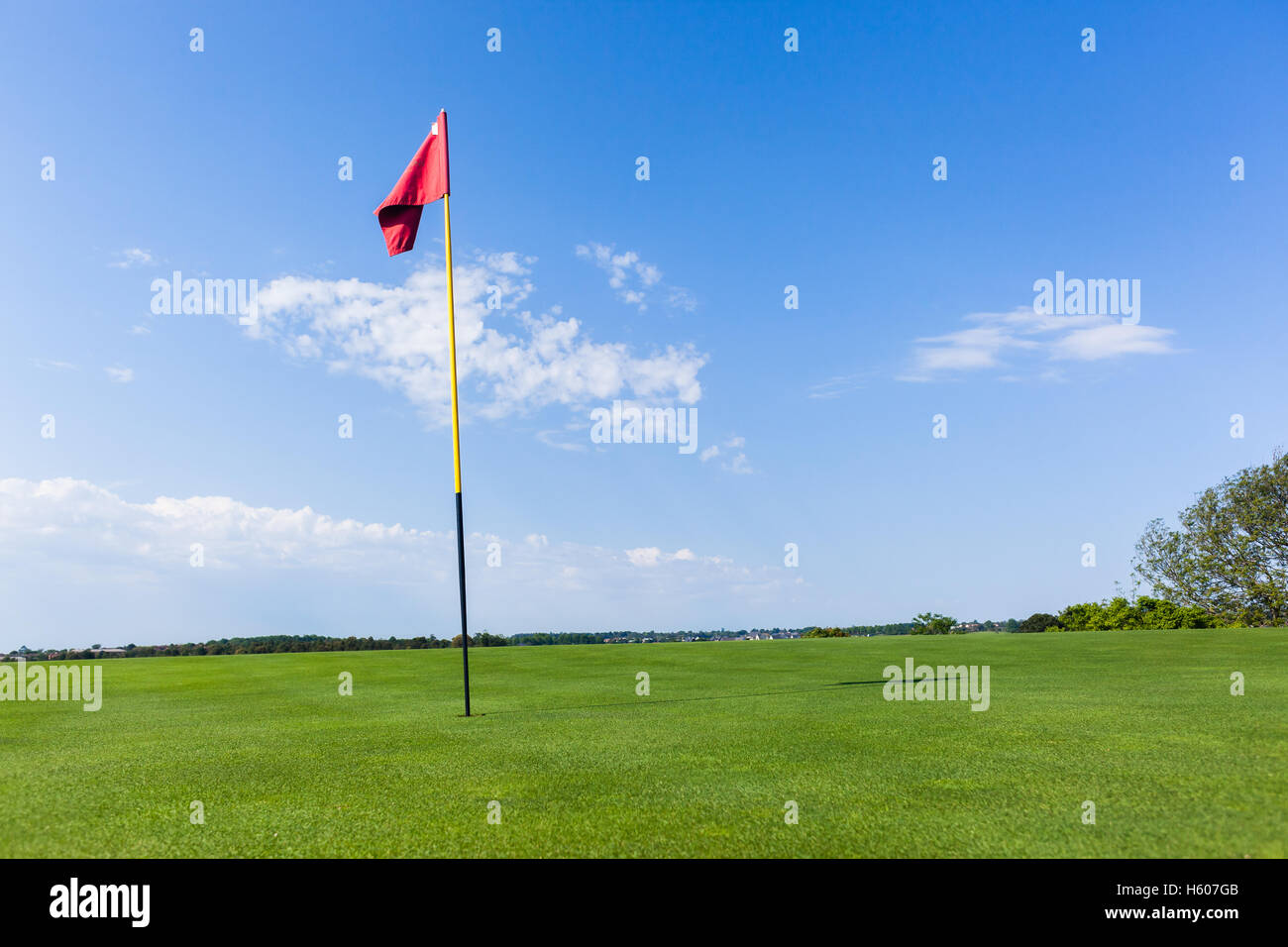 Golf course hole putting green flag stick hole closeup photo blue sky