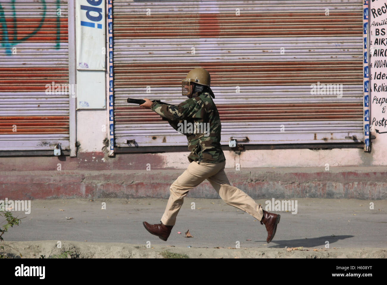 Srinagar, India. 21st Oct, 2016. A police official taking position while chasing the stone-pelters to fire tear gas canister to disperse them. Tensions engulfed Valley on July 8 when a Hizb commander Burhan Wani was killed in an encounter with government forces. More than 91 civilians were killed since the unrest while above 15,000 civilians were maimed. Credit:  Umer Asif/Pacific Press/Alamy Live News Stock Photo