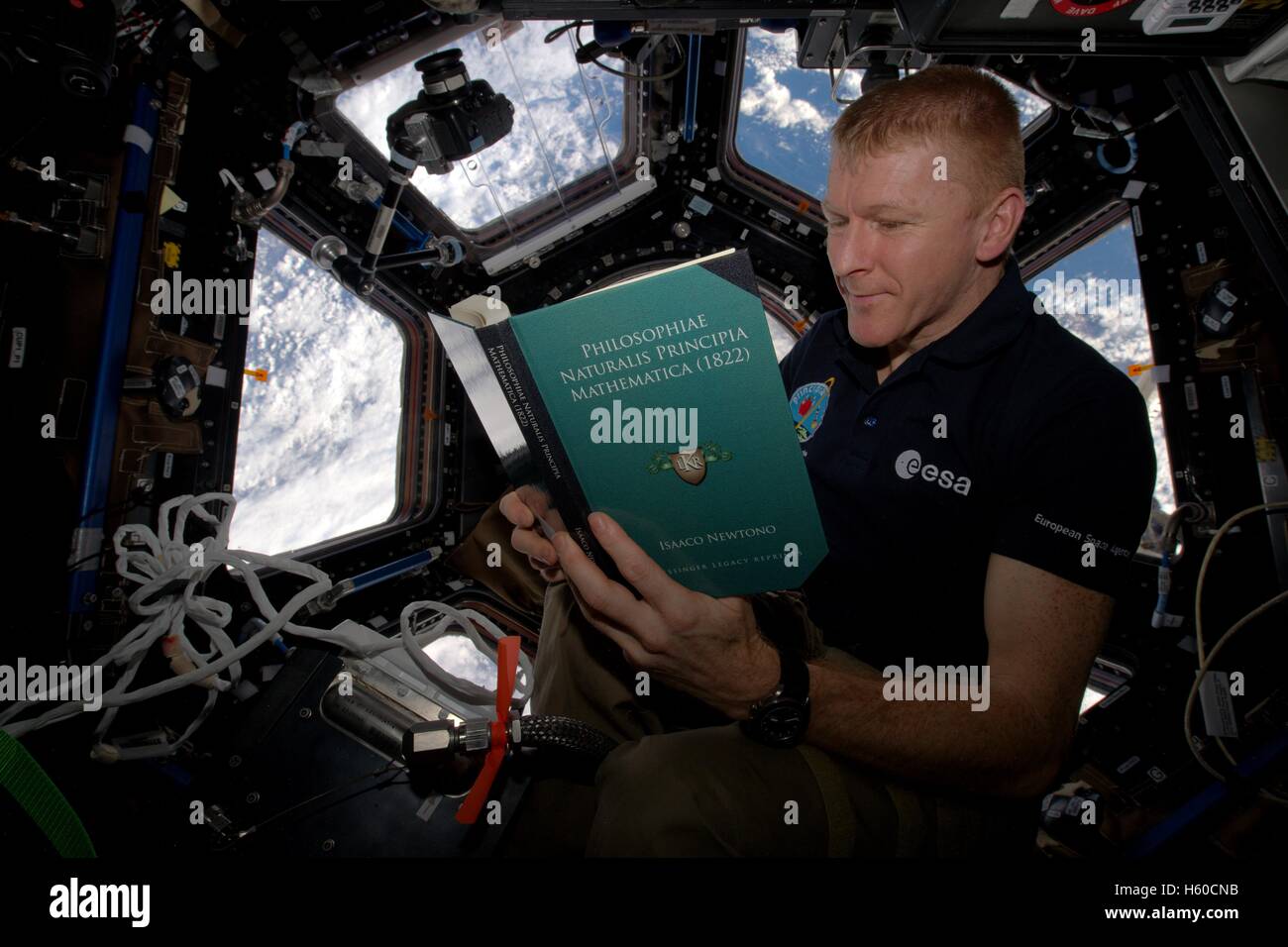 NASA International Space Station Expedition 46 British astronaut Tim Peake reads Principe Mathematica by Isaac Newton during World Book Day February 28, 2016 while in Earth orbit. Stock Photo