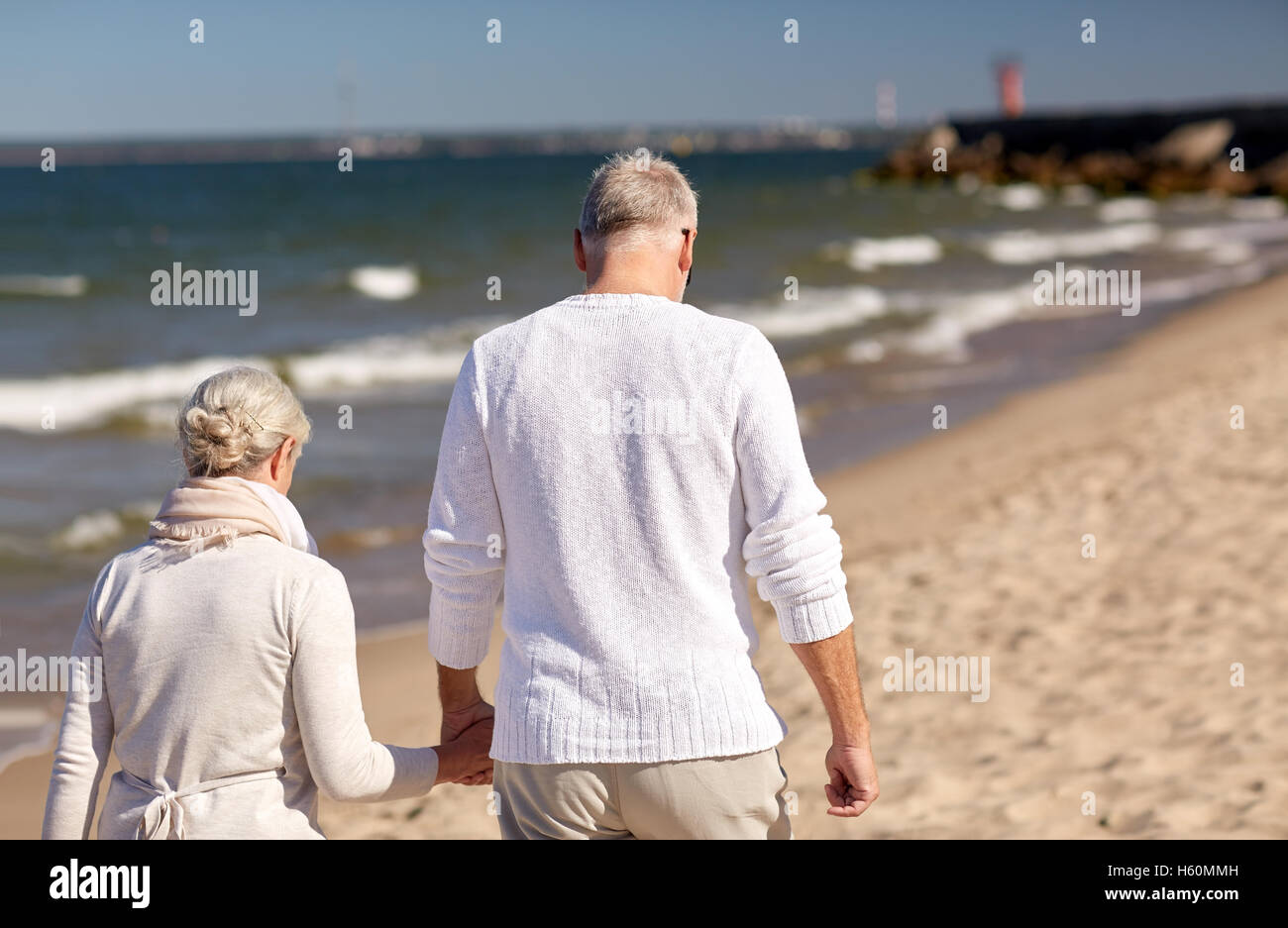 Old couple walking along beach hi-res stock photography and images - Alamy