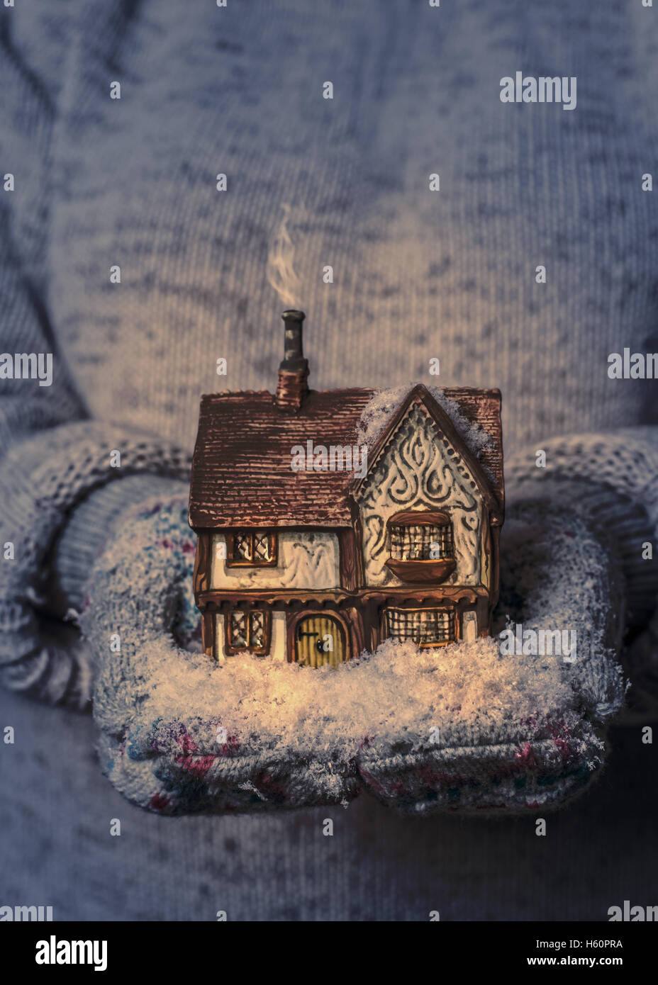 Winter cottage at night in gloved hands with snow Stock Photo