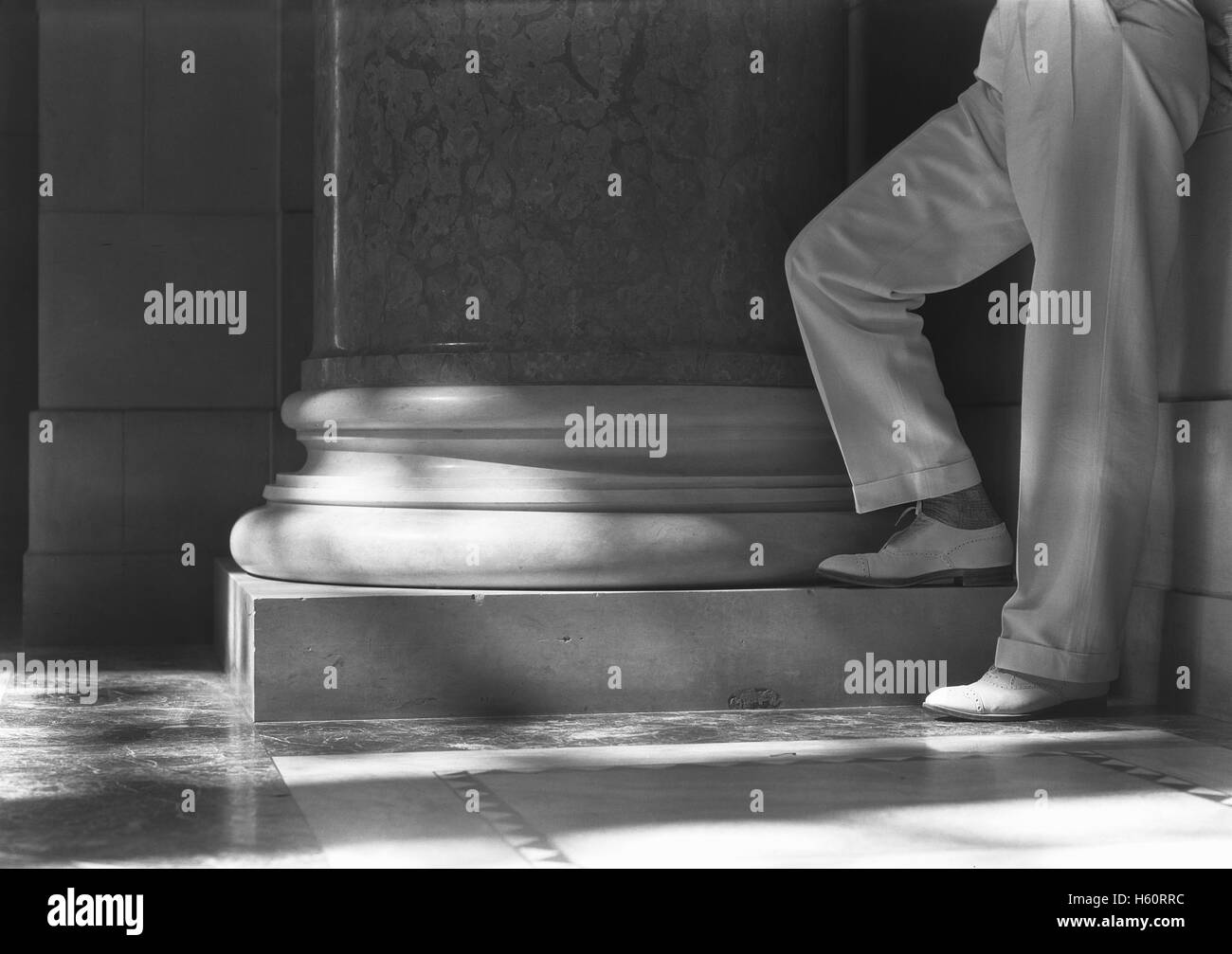 View of Man's Legs in Cuffed Trousers Standing at Column Base, State Capitol Building, Lincoln, Nebraska, USA, by Samuel H. Gottscho, June 1934 Stock Photo
