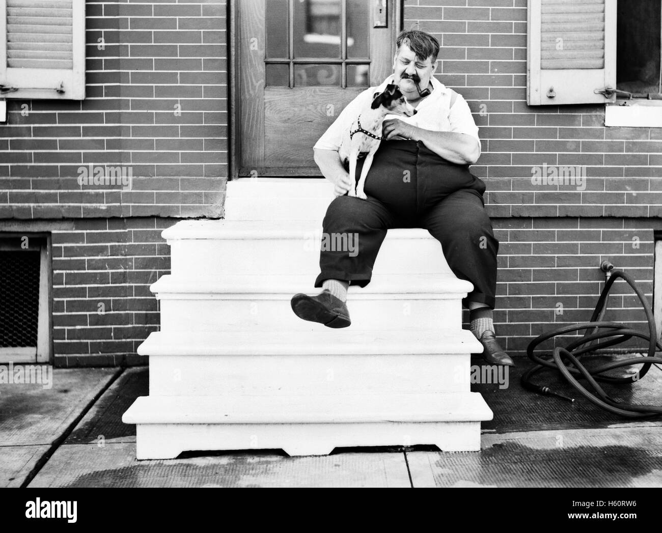 Heavy Man with Dog in front of Row House, Baltimore, Maryland, USA, John Vachon for Office of War Information, July 1938 Stock Photo