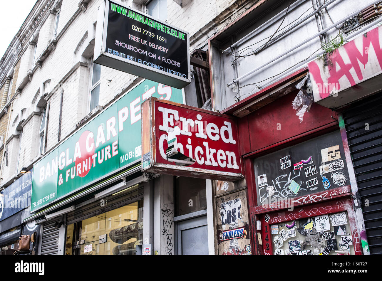 Old fried chicken shop sign next to a carpet and furniture shop in East London Stock Photo