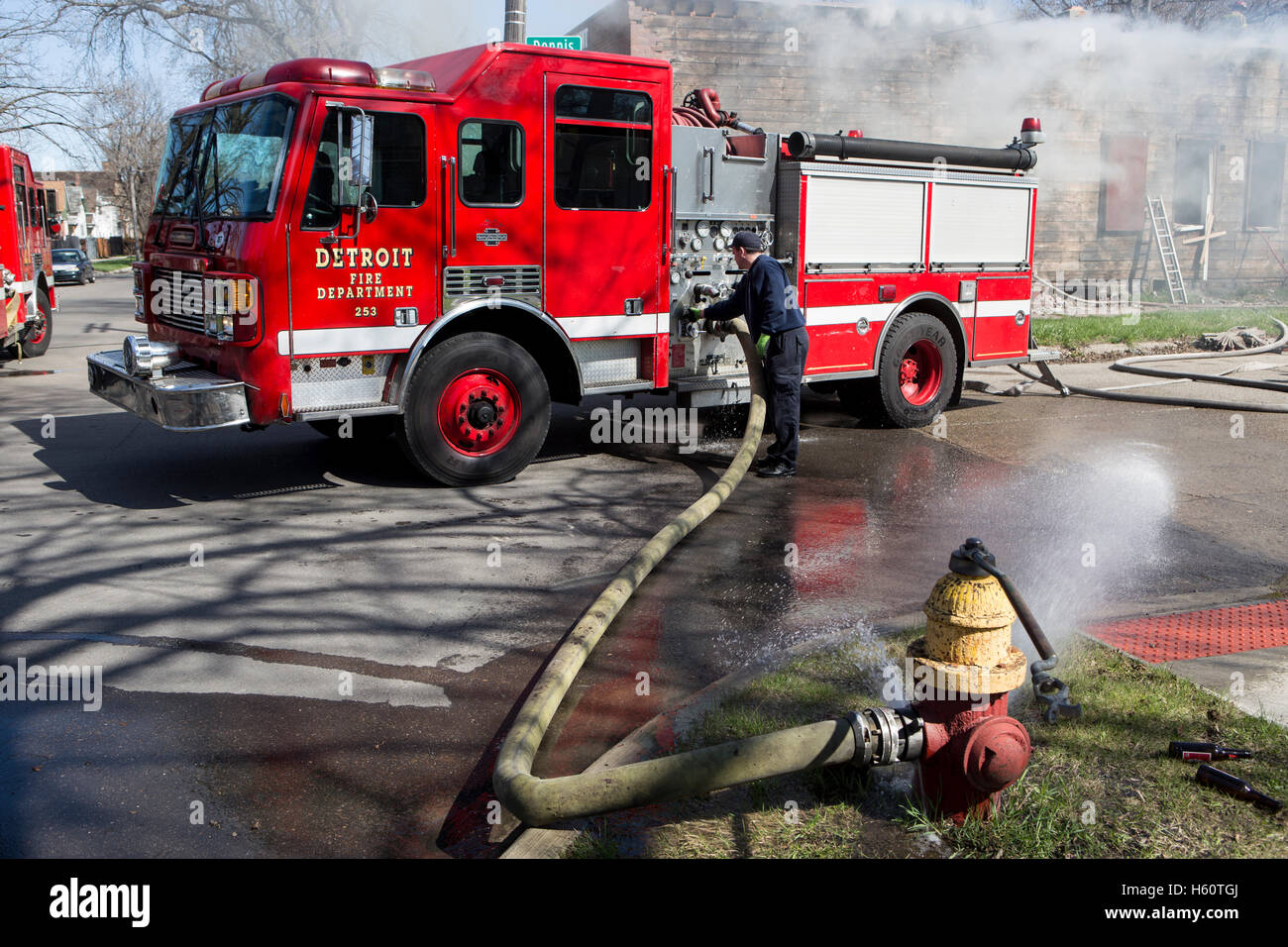 Fire engine pumper hooked to fire hydrant, drafting and pumping water, at house fire, Detroit, Michigan USA Stock Photo