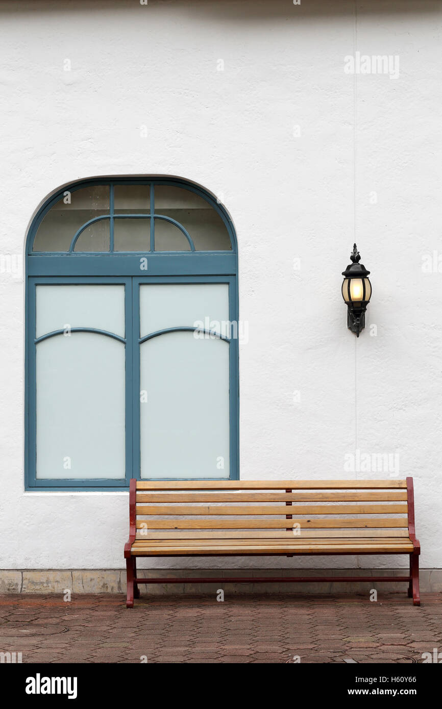 outdoor bench with white wall on brick street Stock Photo