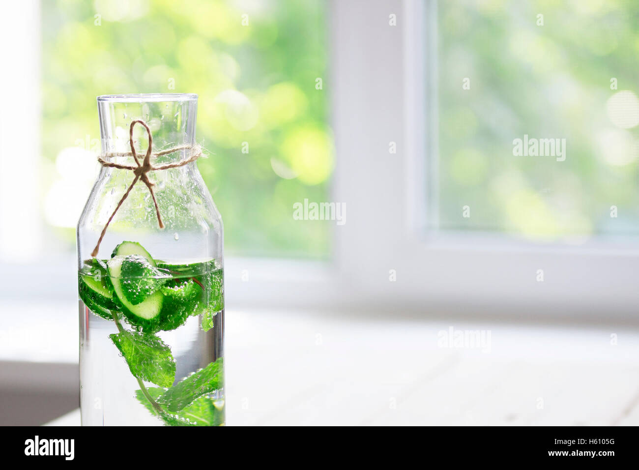 Nutritious detox water or lemonade with cucumber and mint on table near window. Copy space for text. Stock Photo