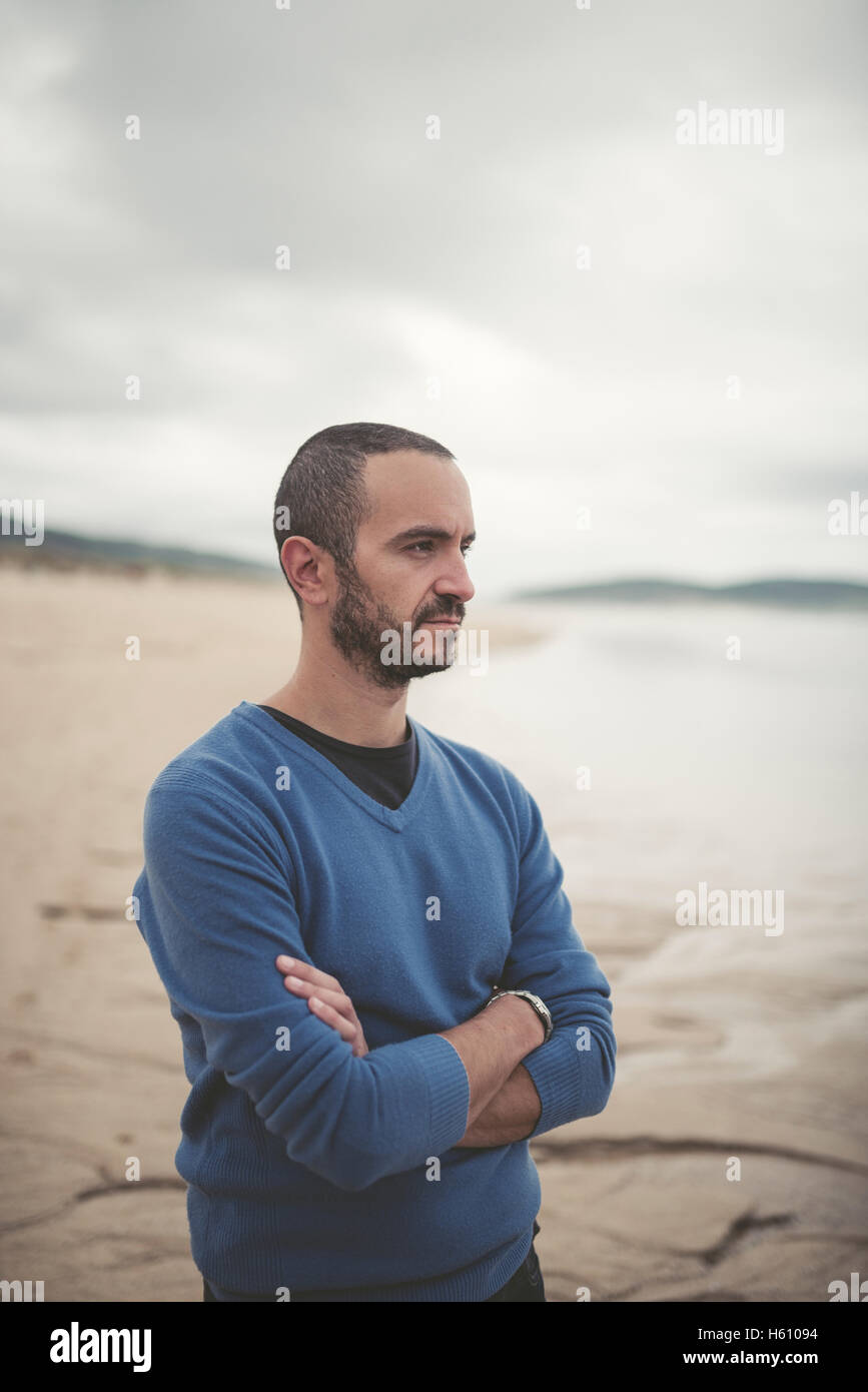 Thoughtful man on the beach, he has arms crossed. Stock Photo
