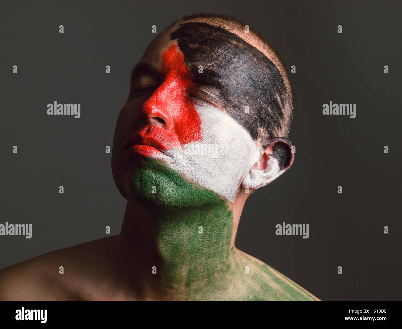 Man with his face painted with Palestinian flag. The man's eyes closed and looking sideways. Stock Photo