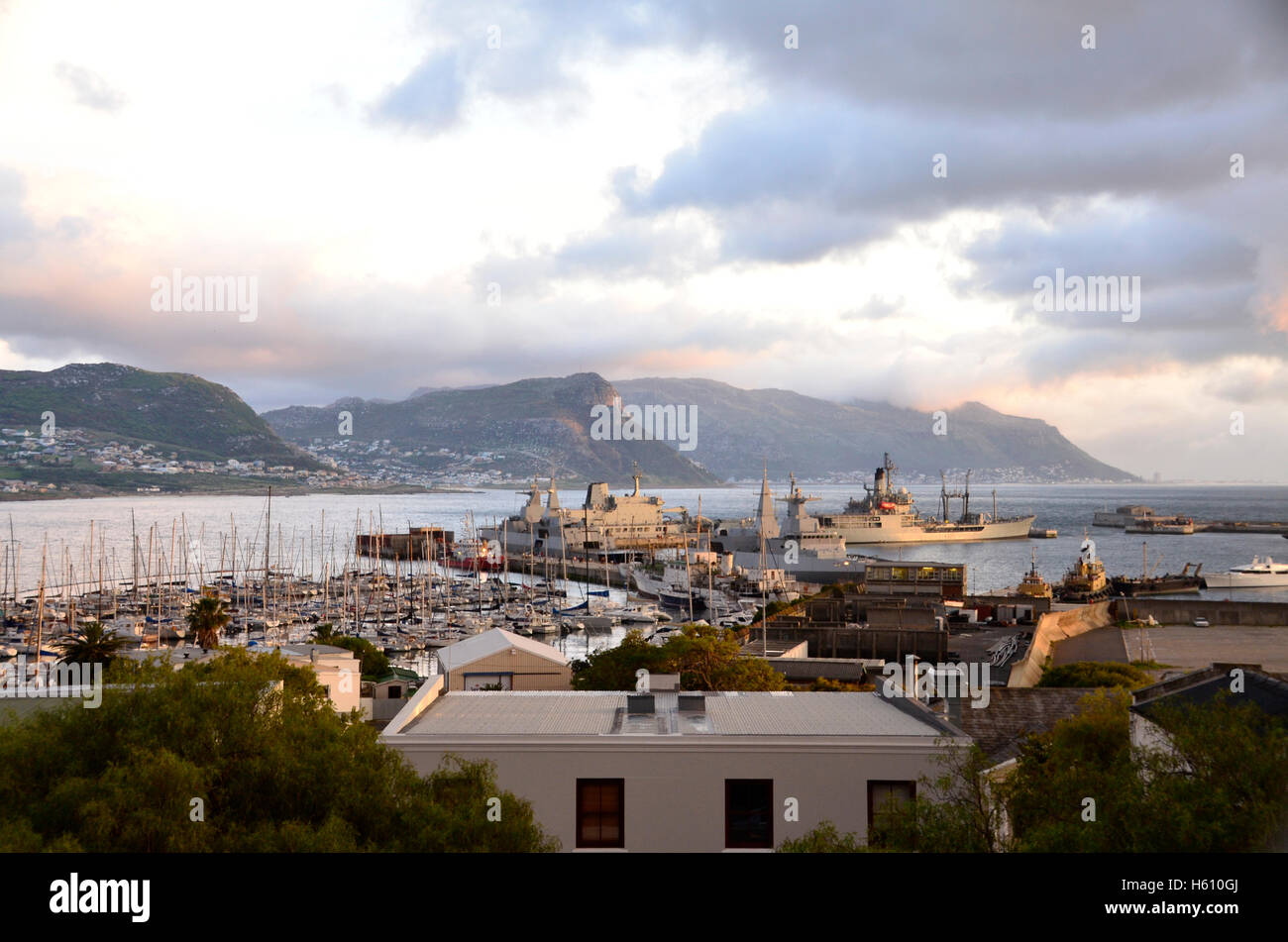 Sunrise on warships in Simon'sTown harbour with Fish Hoek and Kalk Bay across the bay Stock Photo