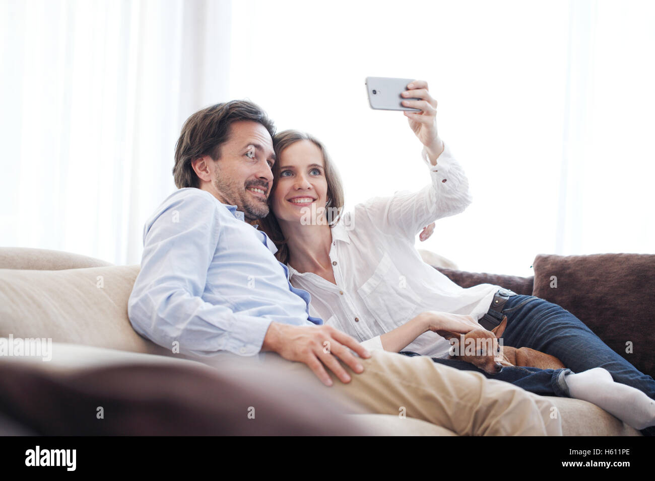 Happy couple taking a selfie together on the couch at home Stock Photo ...