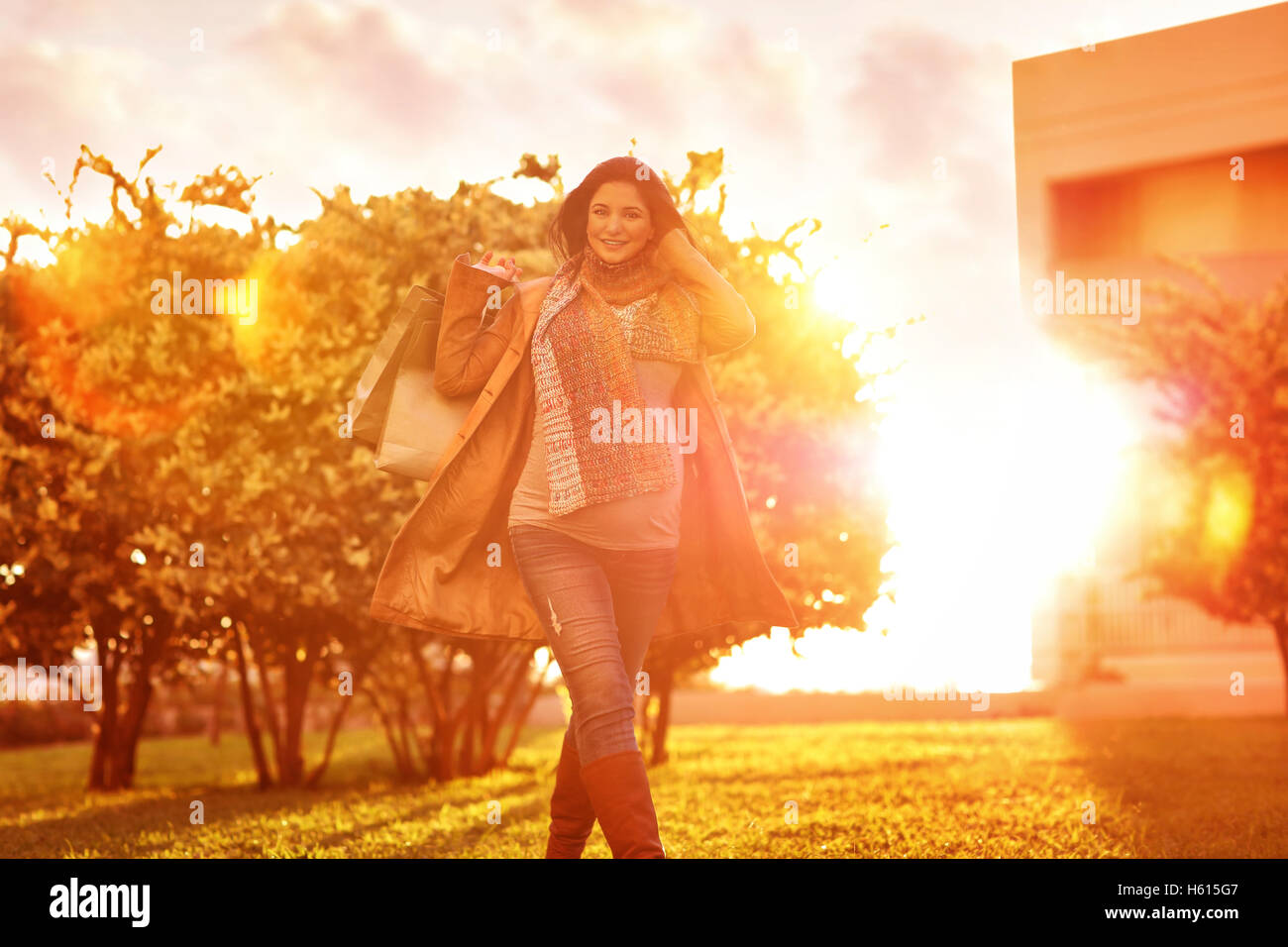 Cheerful pregnant woman with shopping bags in the garden in bright sunny day, autumn season sale, doing purchase for a baby Stock Photo