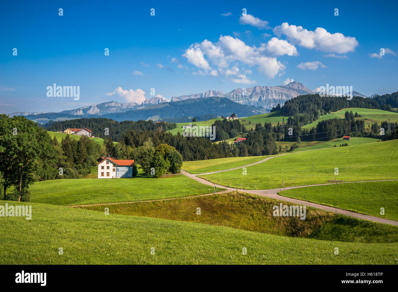 Beautiful view of idyllic mountain scenery in the Alps with green meadows and famous Saentis summit in the background on a sunny Stock Photo