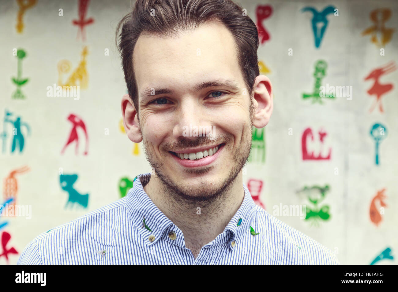 Portrait of a happy young man standing against a colourful funky background Stock Photo