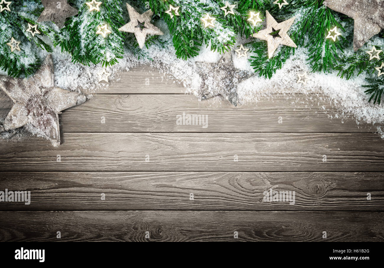Christmas background in natural, elegant and simple wood style, with a border of fir branches, wooden stars and snow Stock Photo