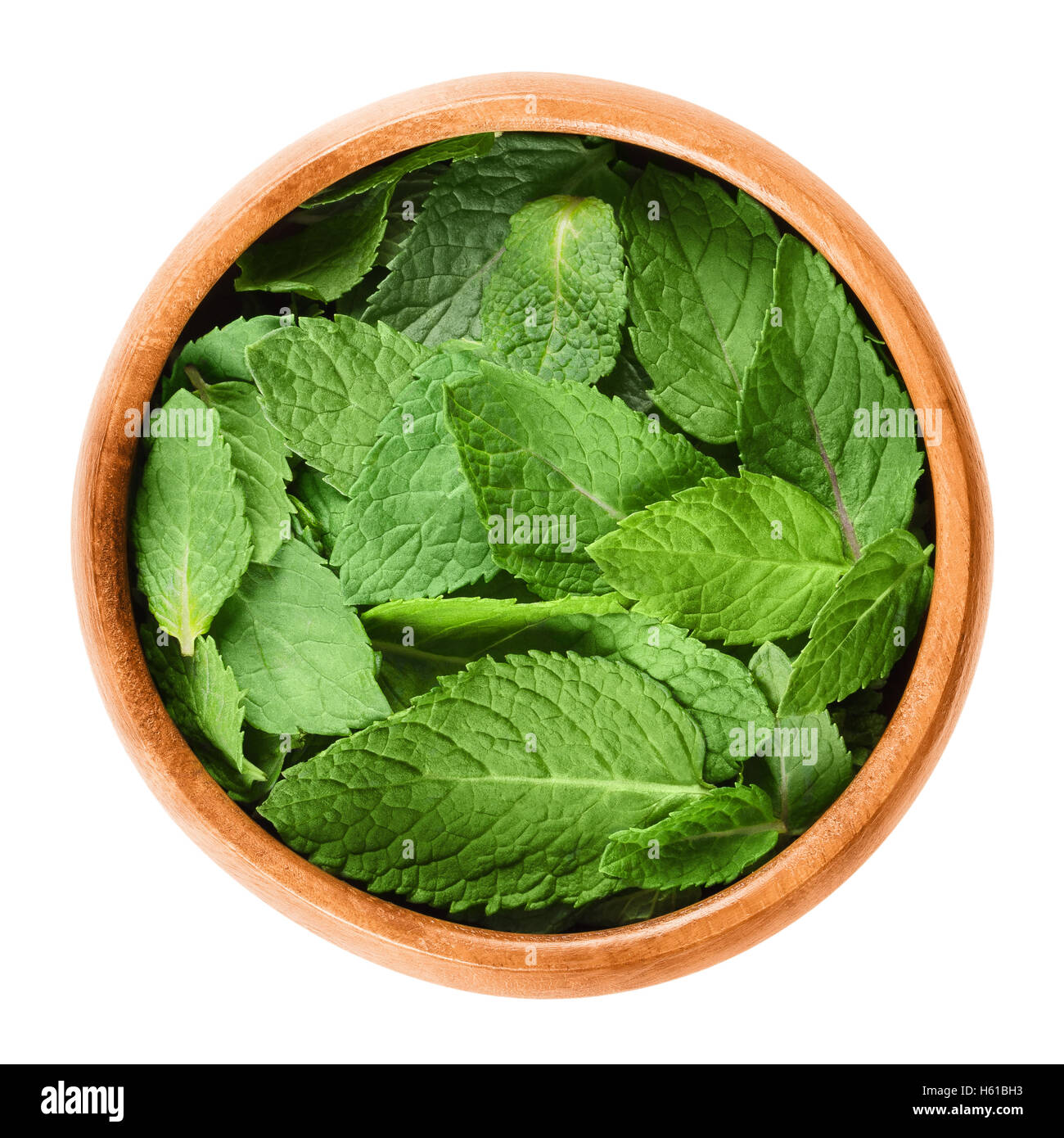 Fresh peppermint leaves in a wooden bowl on white background. Green Mentha piperita, an edible herb. Stock Photo