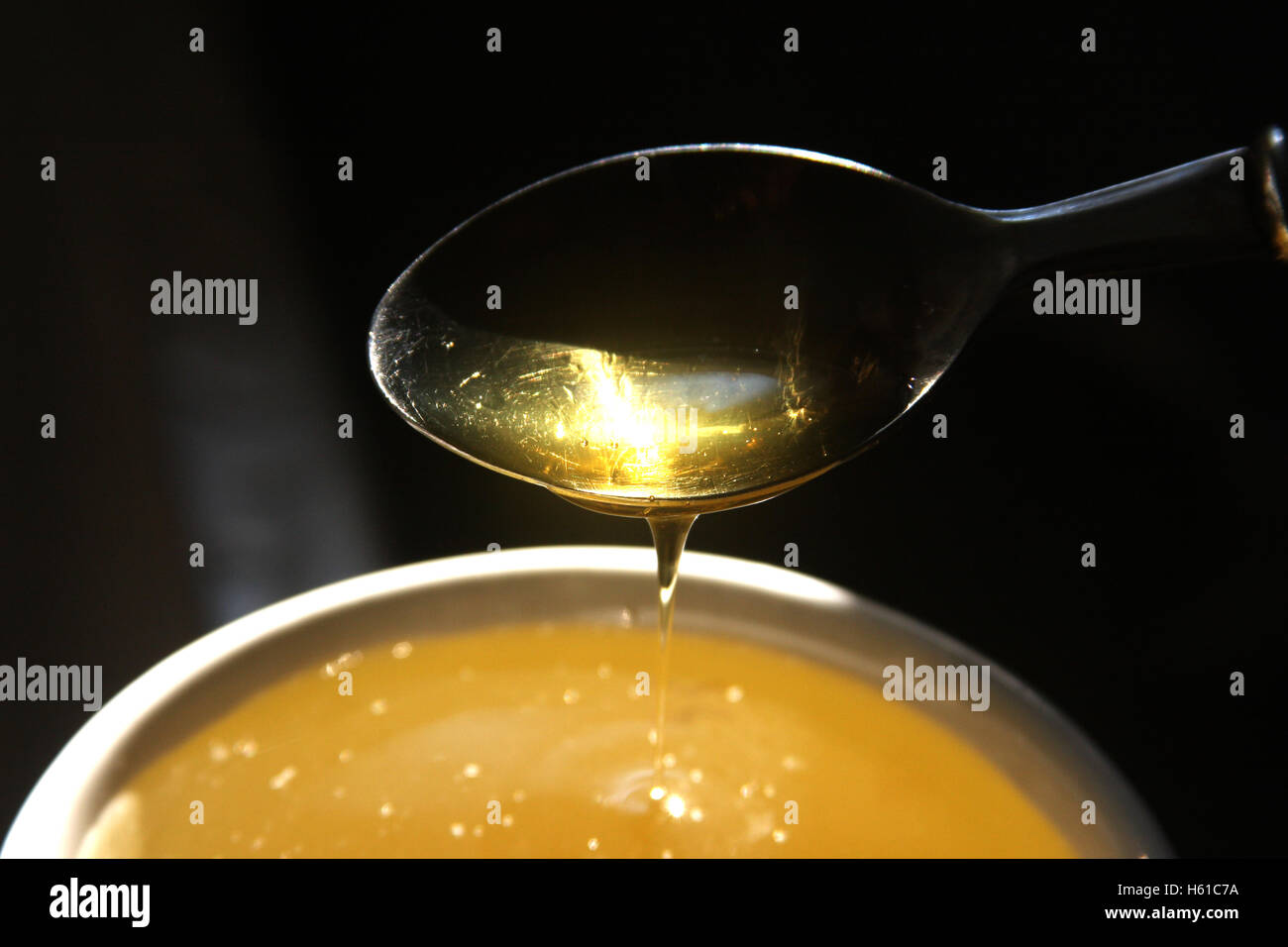 Teaspoon filled with honey poured into cup of tea Stock Photo - Alamy