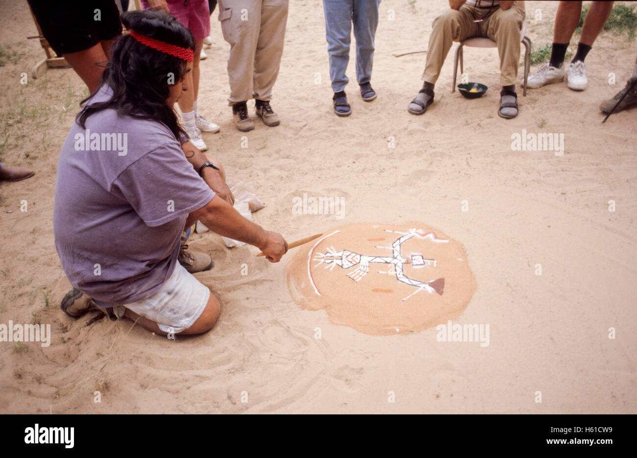 Navajo guide creating a sand painting in front of group of hikers, Canyon de Chelly National Monument, Arizona Stock Photo