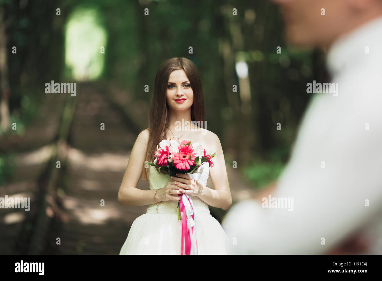 Closeup portrait of beautiful bride with wedding bouquet isolated at green natural summer field background Stock Photo