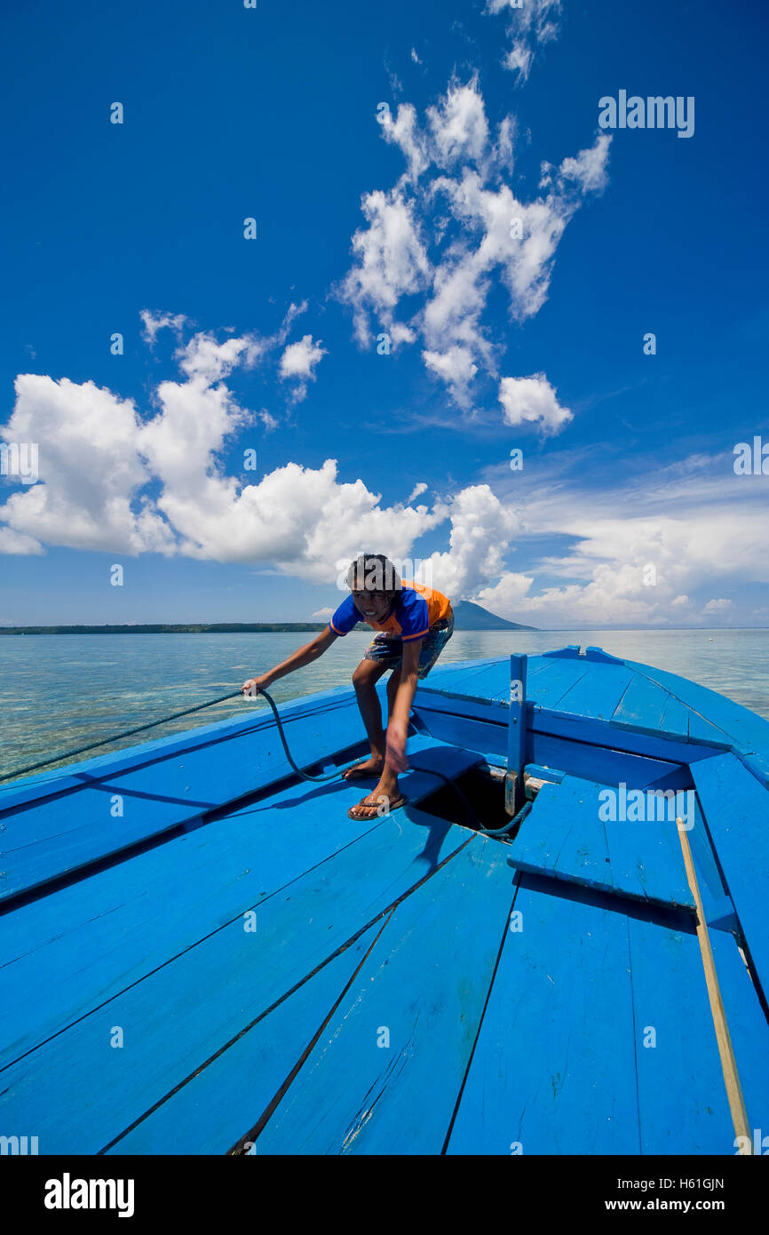 Young woman heaving anchor of a boat, Siladen island, Sulawesi, Indonesia, Southeast Asia Stock Photo