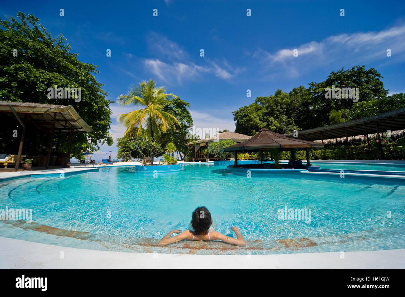 Young woman relaxing in swimming pool, Siladen island, Sulawesi, Indonesia, Southeast Asia Stock Photo
