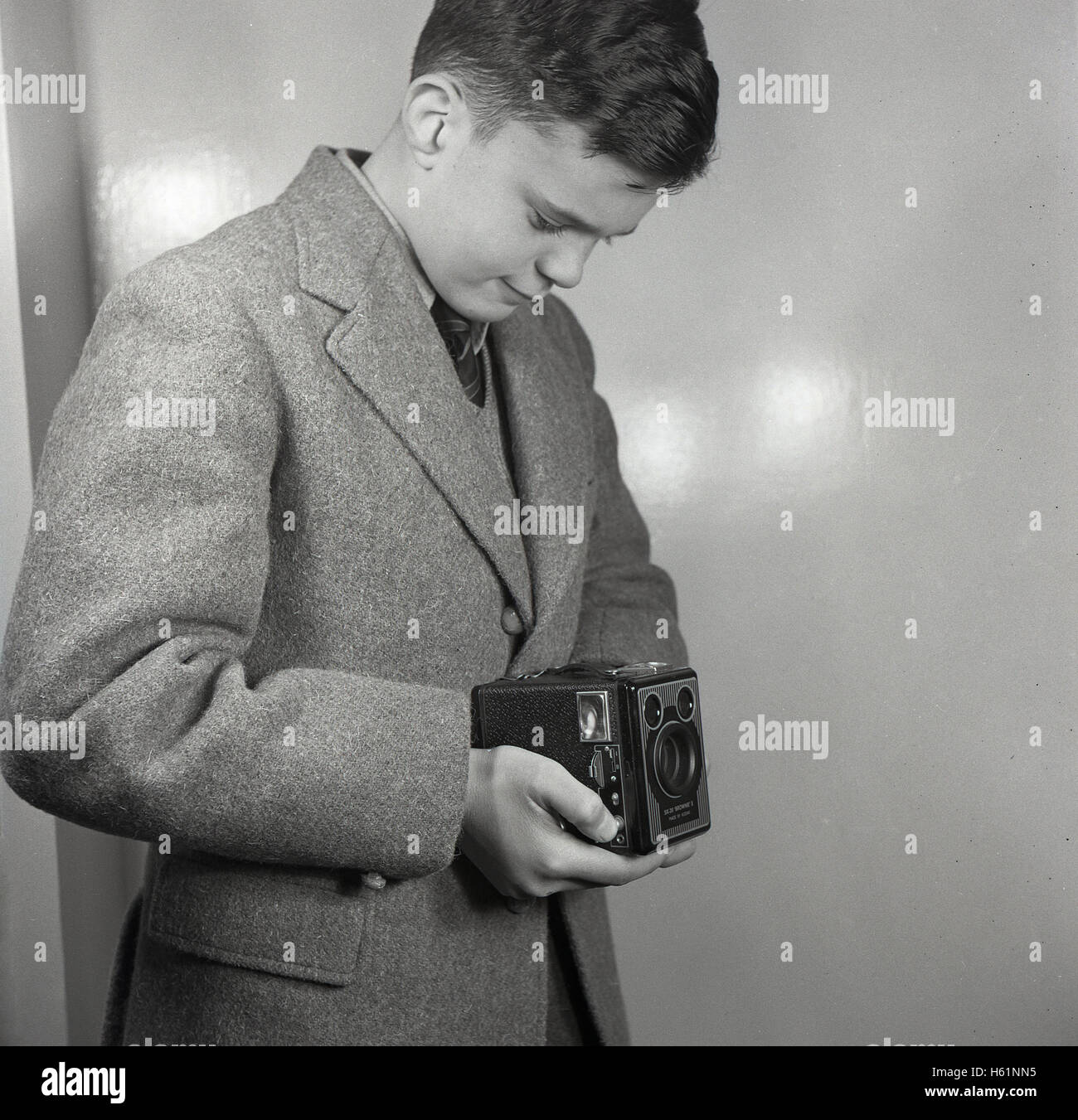 Early 1950s, historical, school boy standing taking a photograph at waist-level using a British made Six-20 'Brownie' E twin-lens reflex box film camera with two viewfinders. Stock Photo