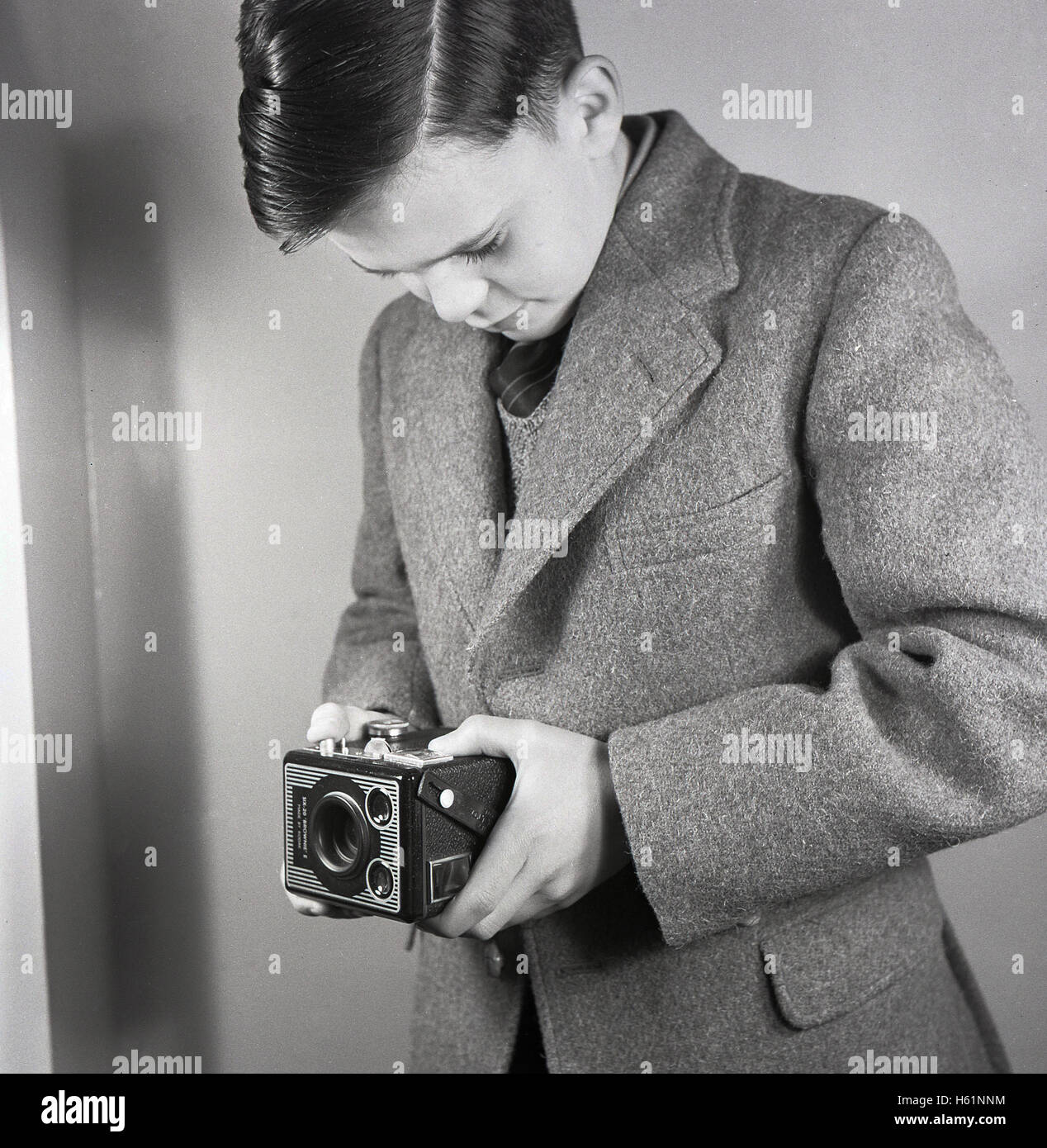 Early 1950s, historical, school boy standing taking a photograph at waist-level using a British made Six-20 'Brownie' E twin-lens reflex box film camera with two viewfinders. Stock Photo