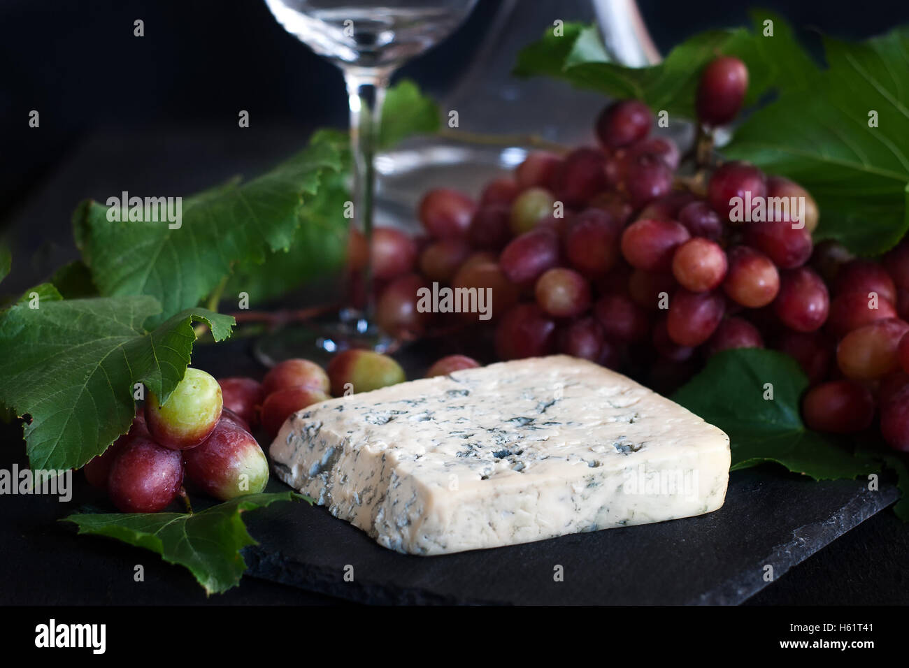 Blue cheese Dorblu with red grape on black background Stock Photo - Alamy