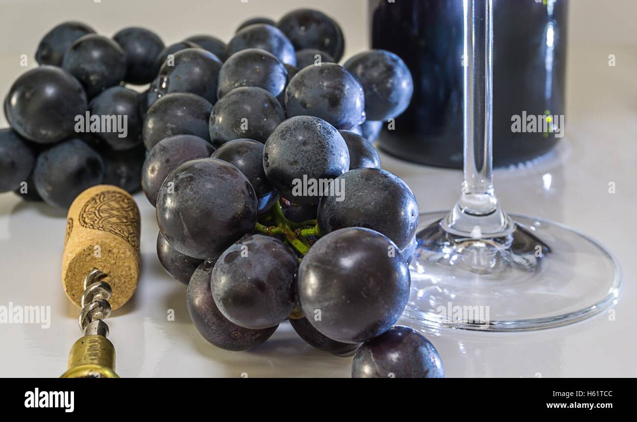 Grapes by the glass, corkscrew and bottle of red wine Stock Photo