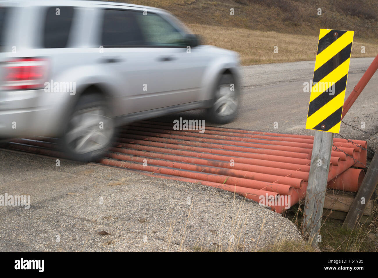 Vehicle crossing a cattle guard to control livestock movement between pastures on a rural road Stock Photo