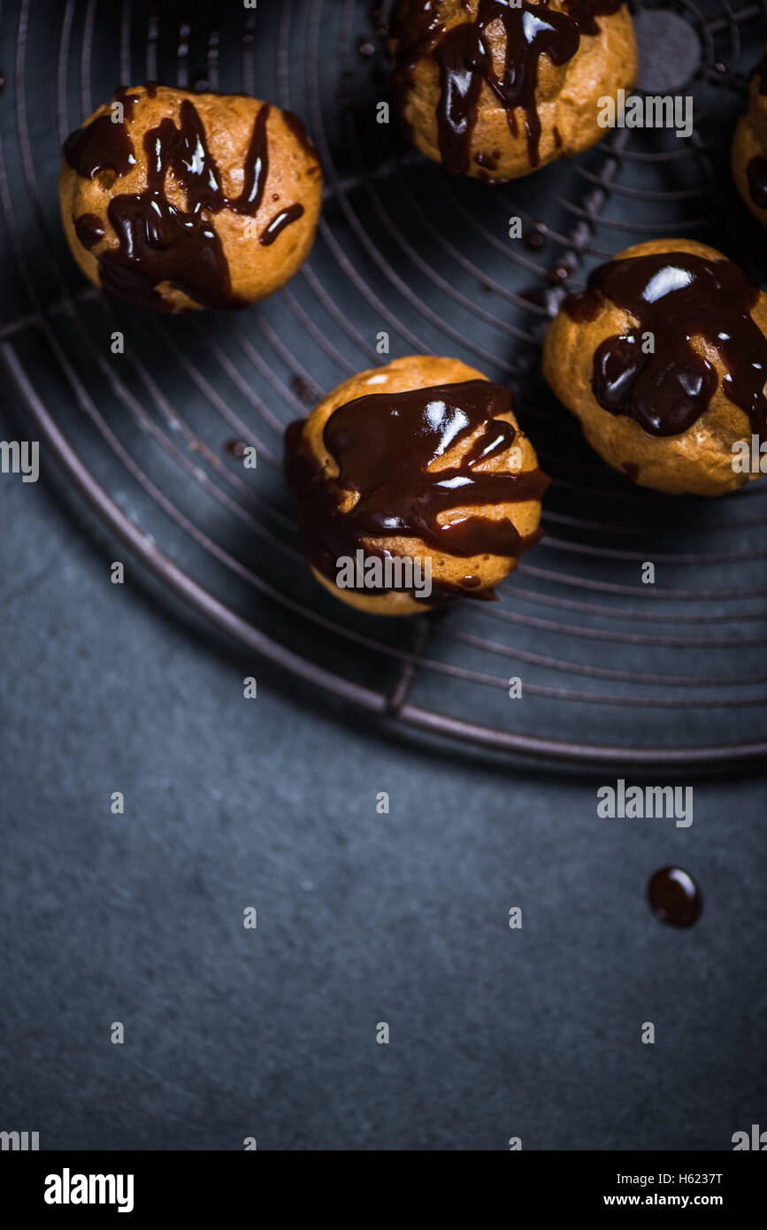 decorating profiteroles with melted hot chocolate on cooling rack Stock ...