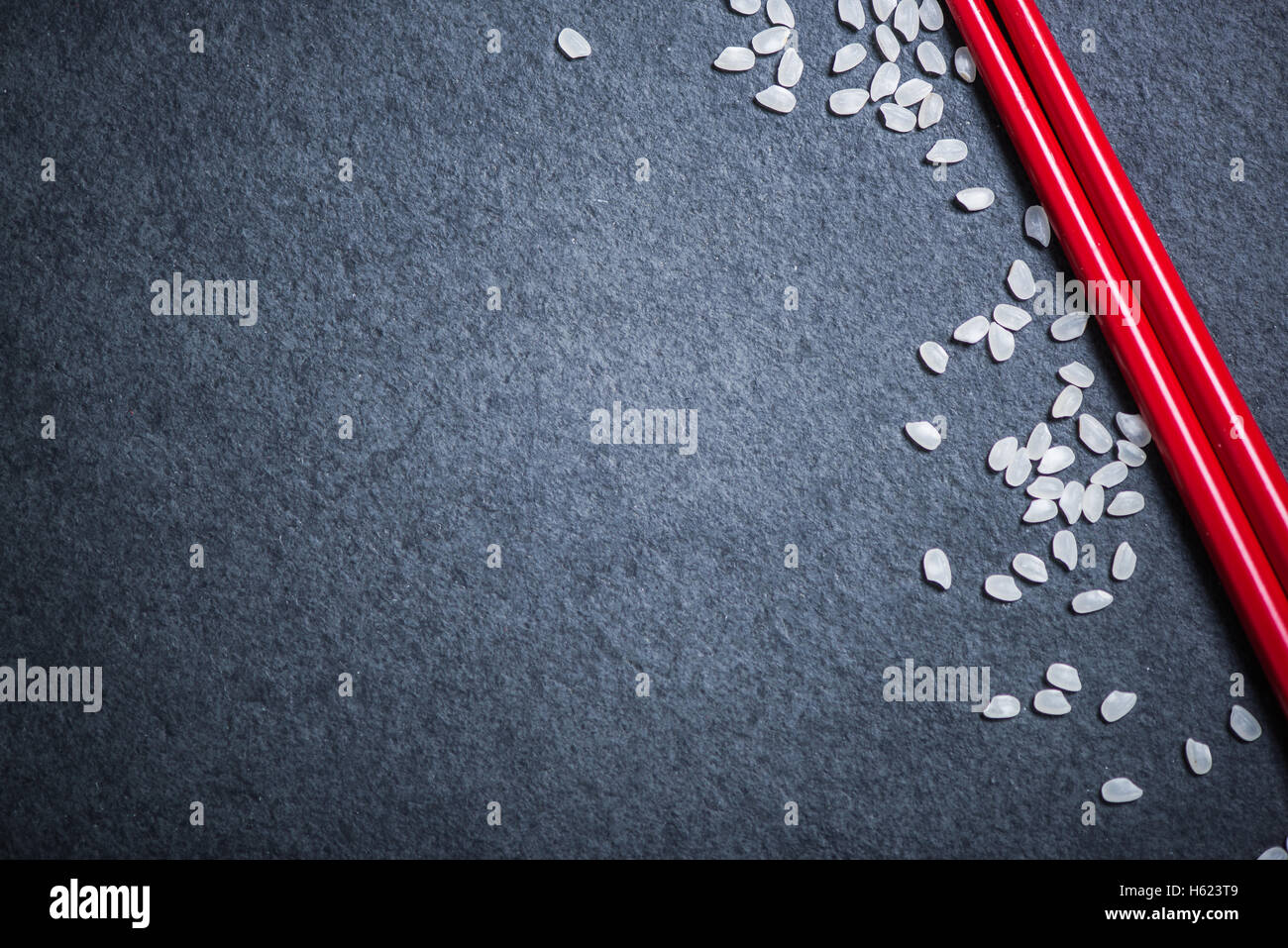 Red chopsticks and rice on dark slate. Border menu background with copy space Stock Photo