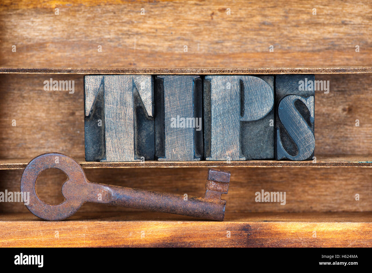 tips word made from wooden letterpress type inside tray with ancient rusty key Stock Photo