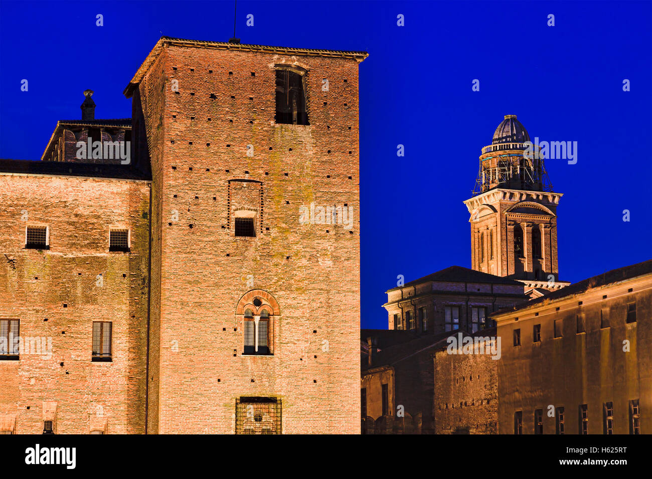 tops of two towers in Mantua city of Italy at sunset - defense tower of San Giorgio castle and Bell tower of Basilica Stock Photo