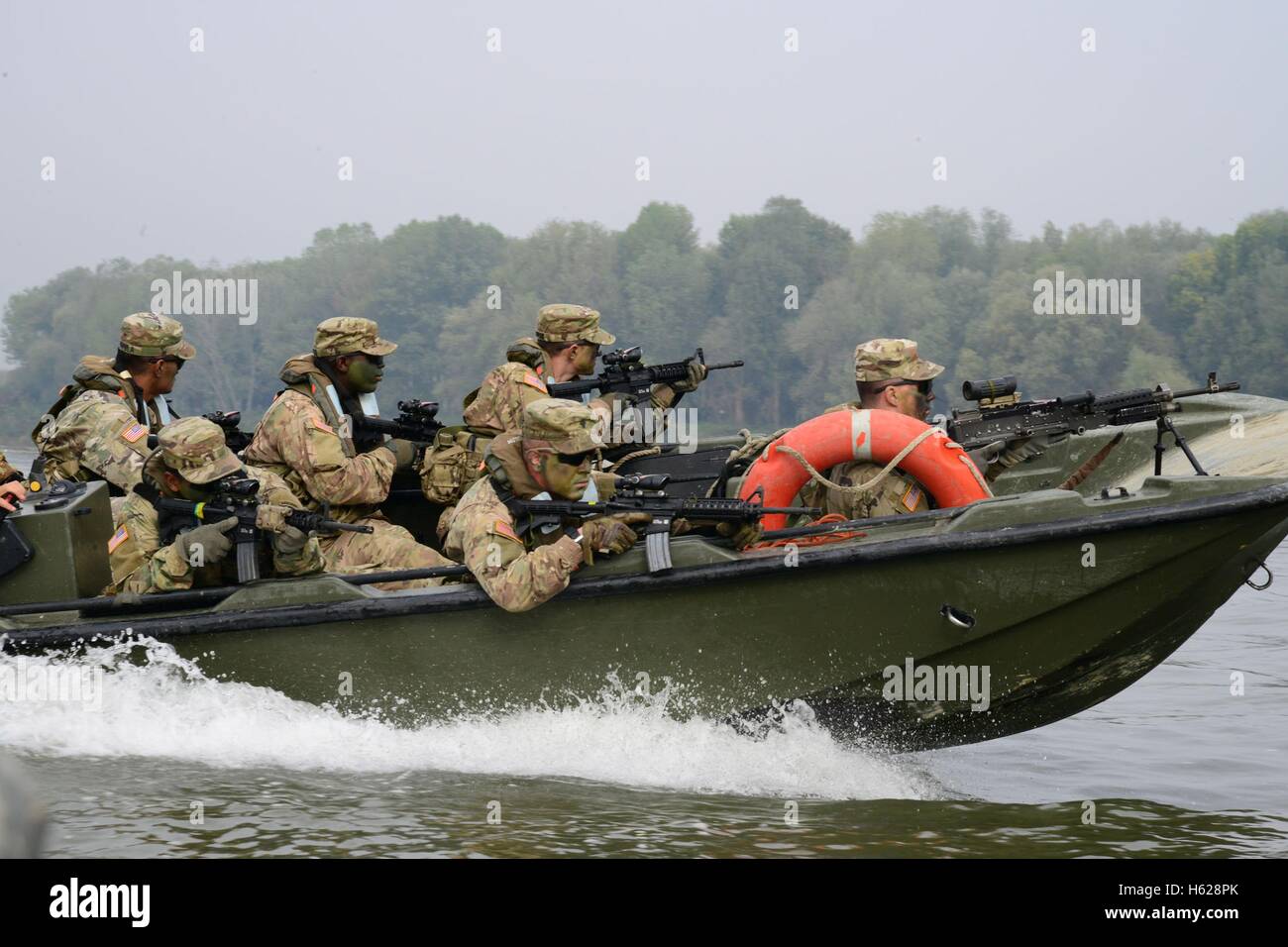 U.S. and Italian soldiers cross a river in a fast boat in combat position during a Livorno Shock training exercise October 17, 2016 in Piacenza, Italy. Stock Photo