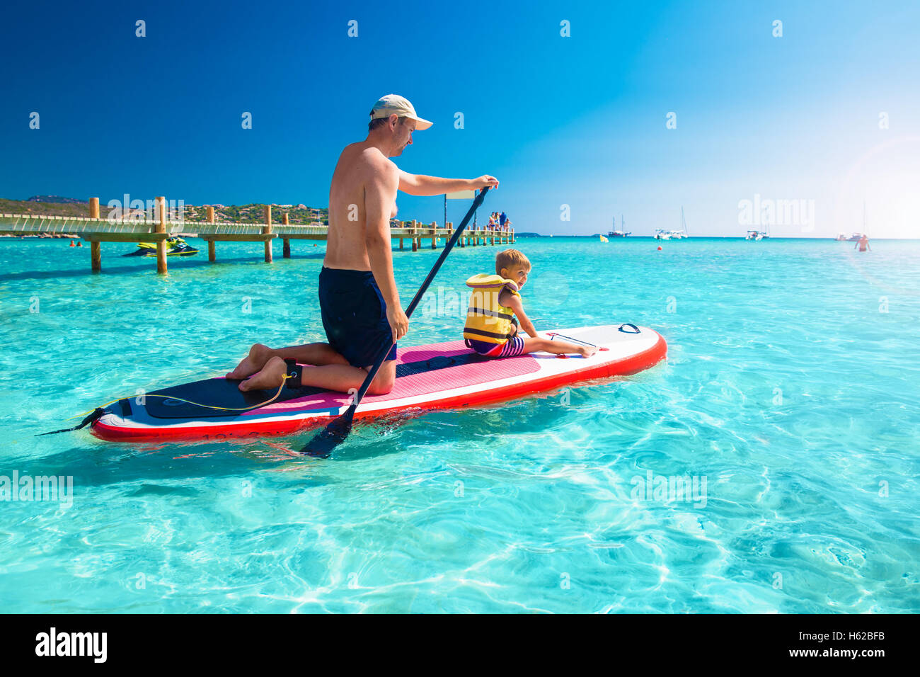 Father with his little happy son having fun on stand up paddle board on Corsica island, France. Stock Photo