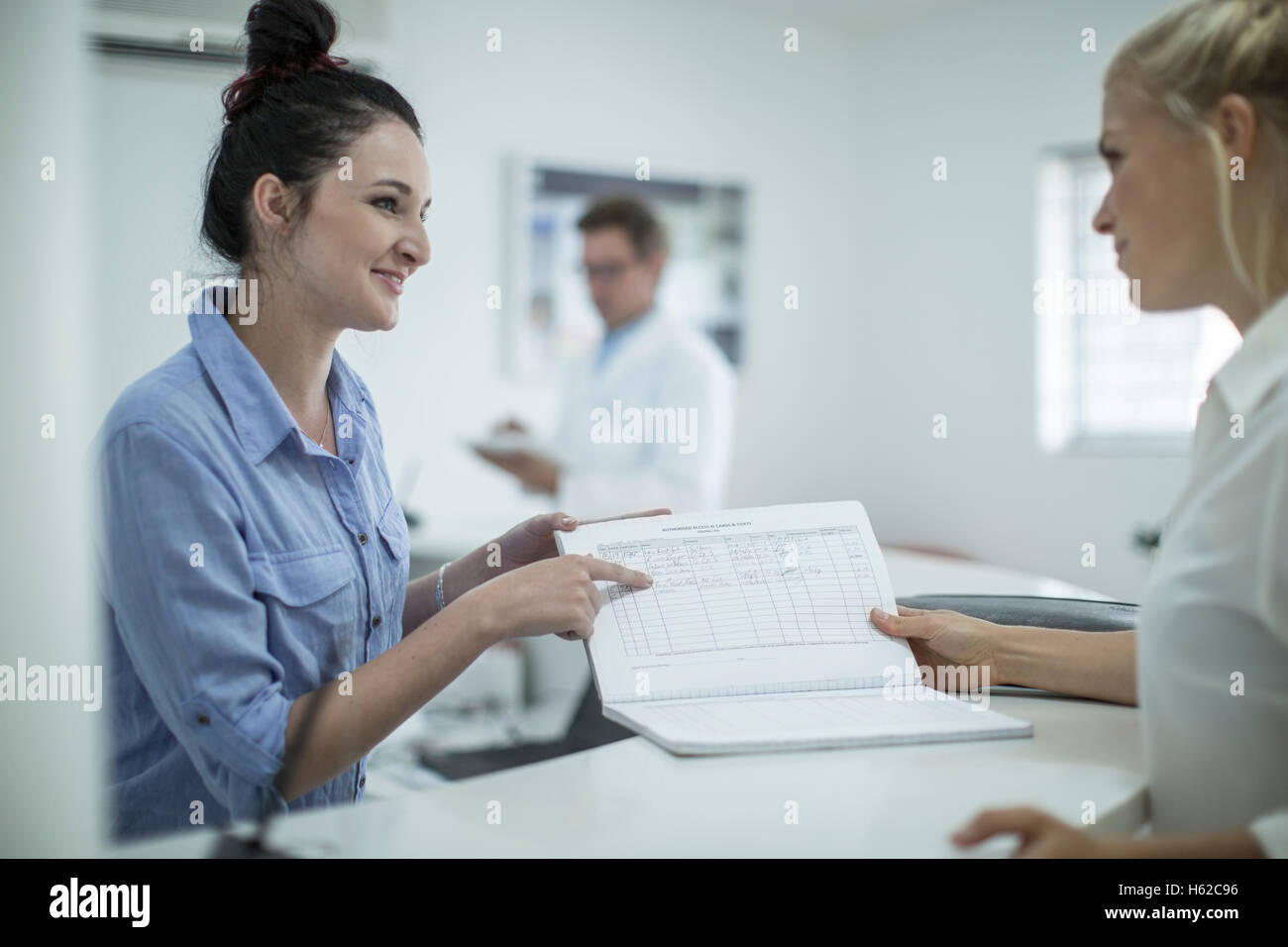 Two women with book at reception Stock Photo