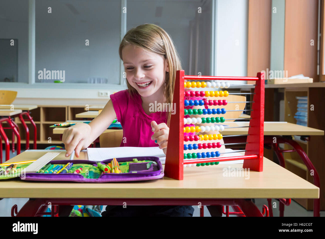 Smiling schoolgirl sitting at desk in her class Stock Photo - Alamy