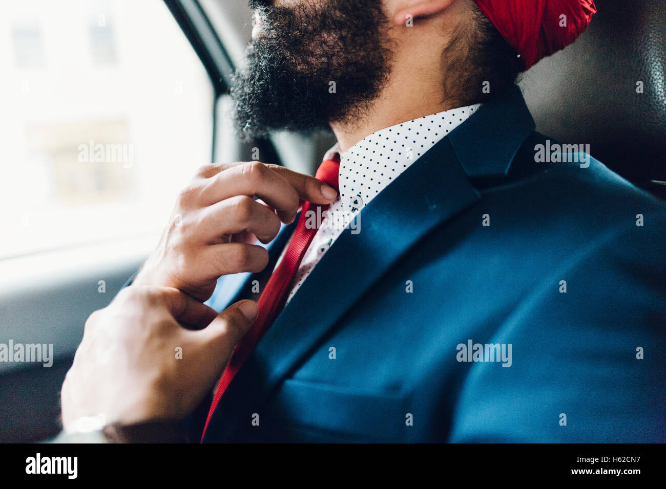 Indian businessman binding tie in a taxi Stock Photo