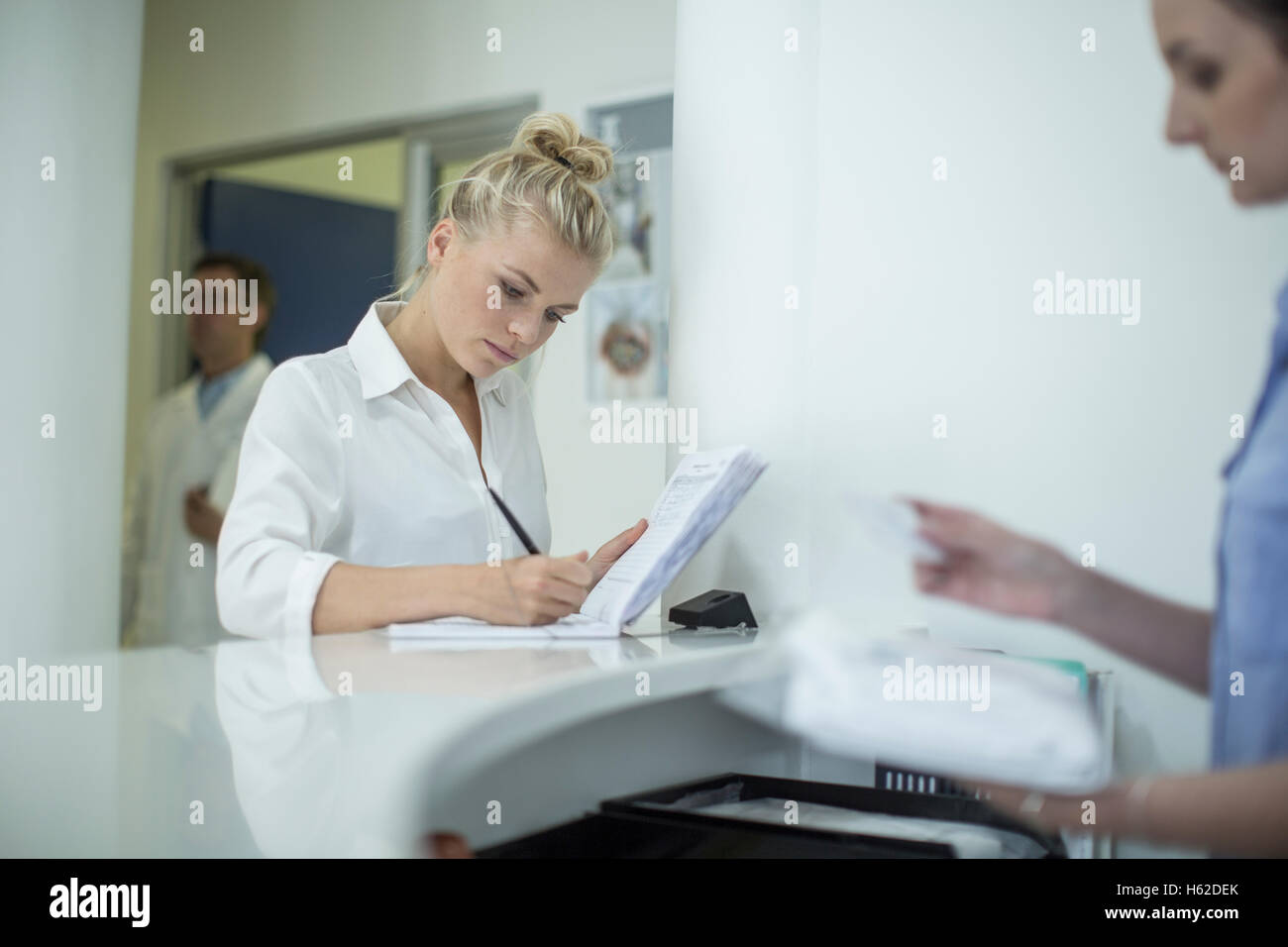 Woman writing in book at reception Stock Photo