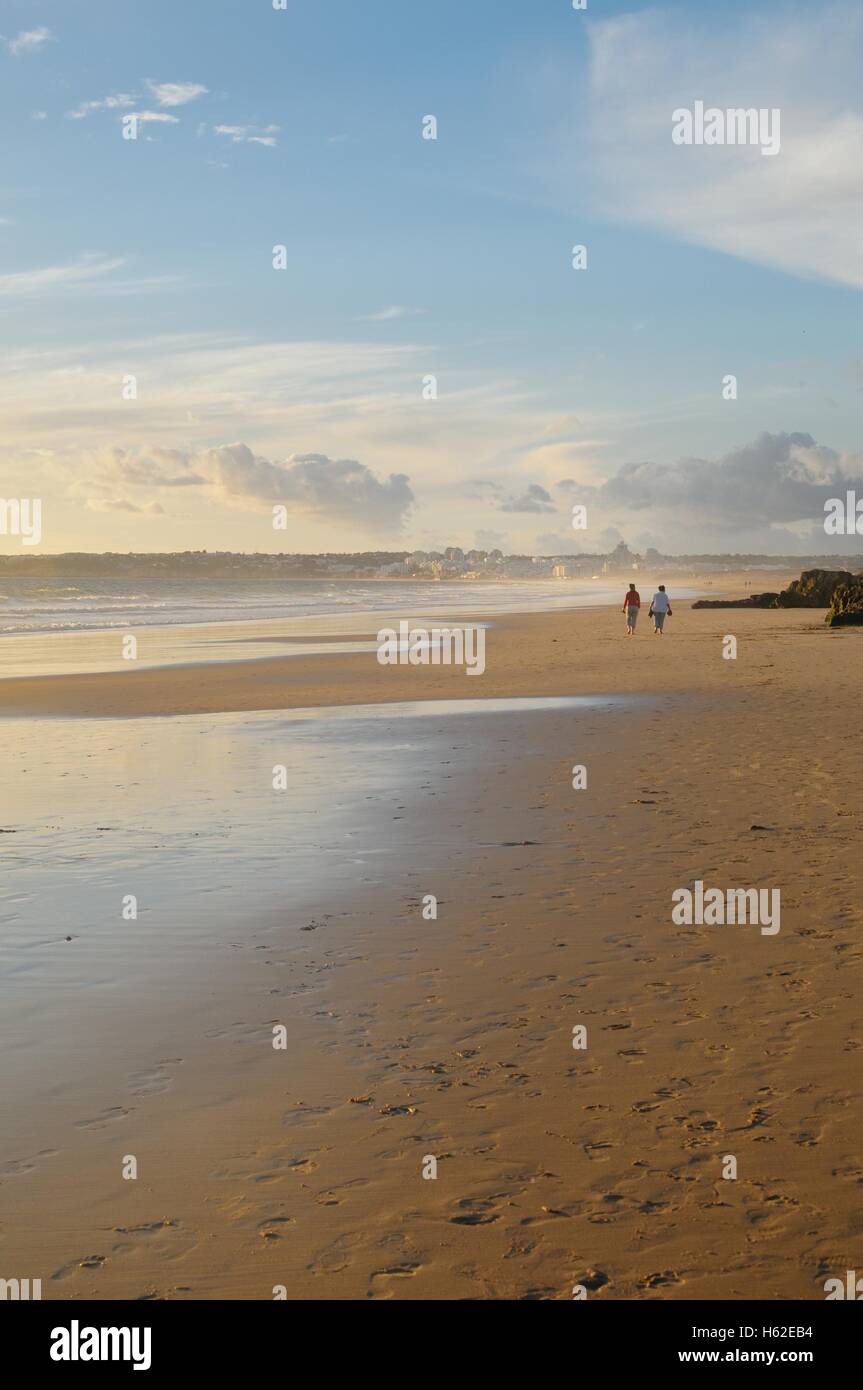 Distant figures walking on beach in the golden evening light Stock Photo