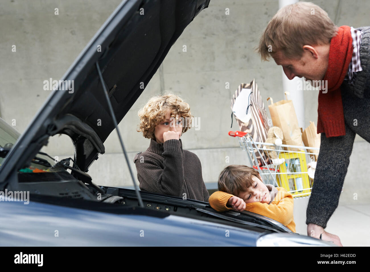 father looking at broken car, while children are waiting Stock Photo
