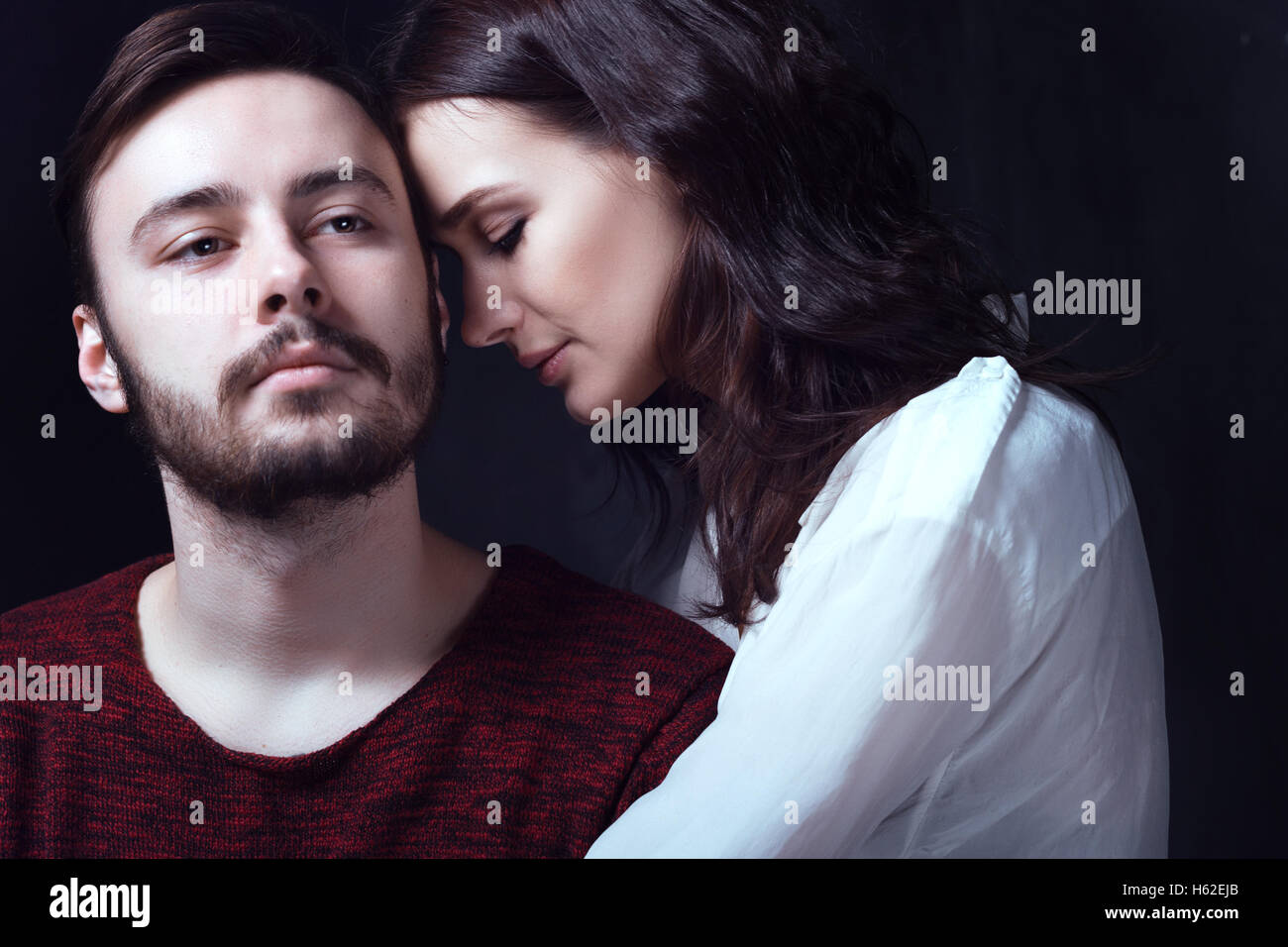 Beautiful cute loving couple is posing in a photostudio with dark walls