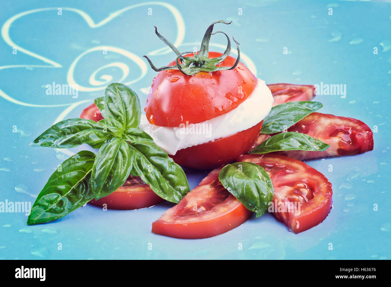 Tomato and mozzarella with basil leaves on a plate Stock Photo - Alamy