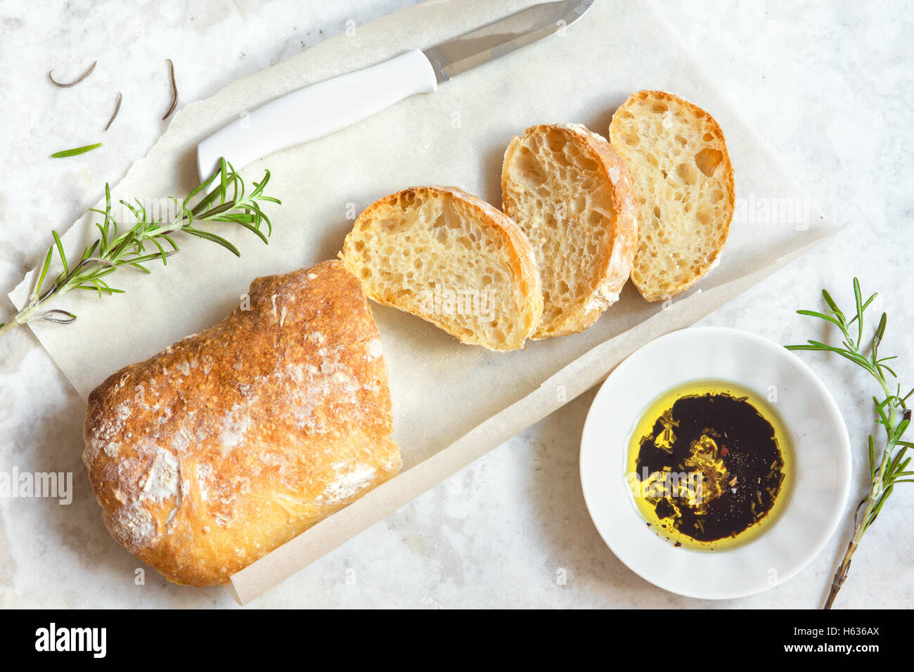 Italian bread Ciabatta with olive oil and rosemary on white marble