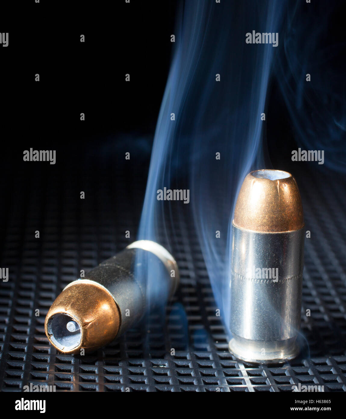 Two handgun cartridges with hollow point bullets and smoke Stock Photo