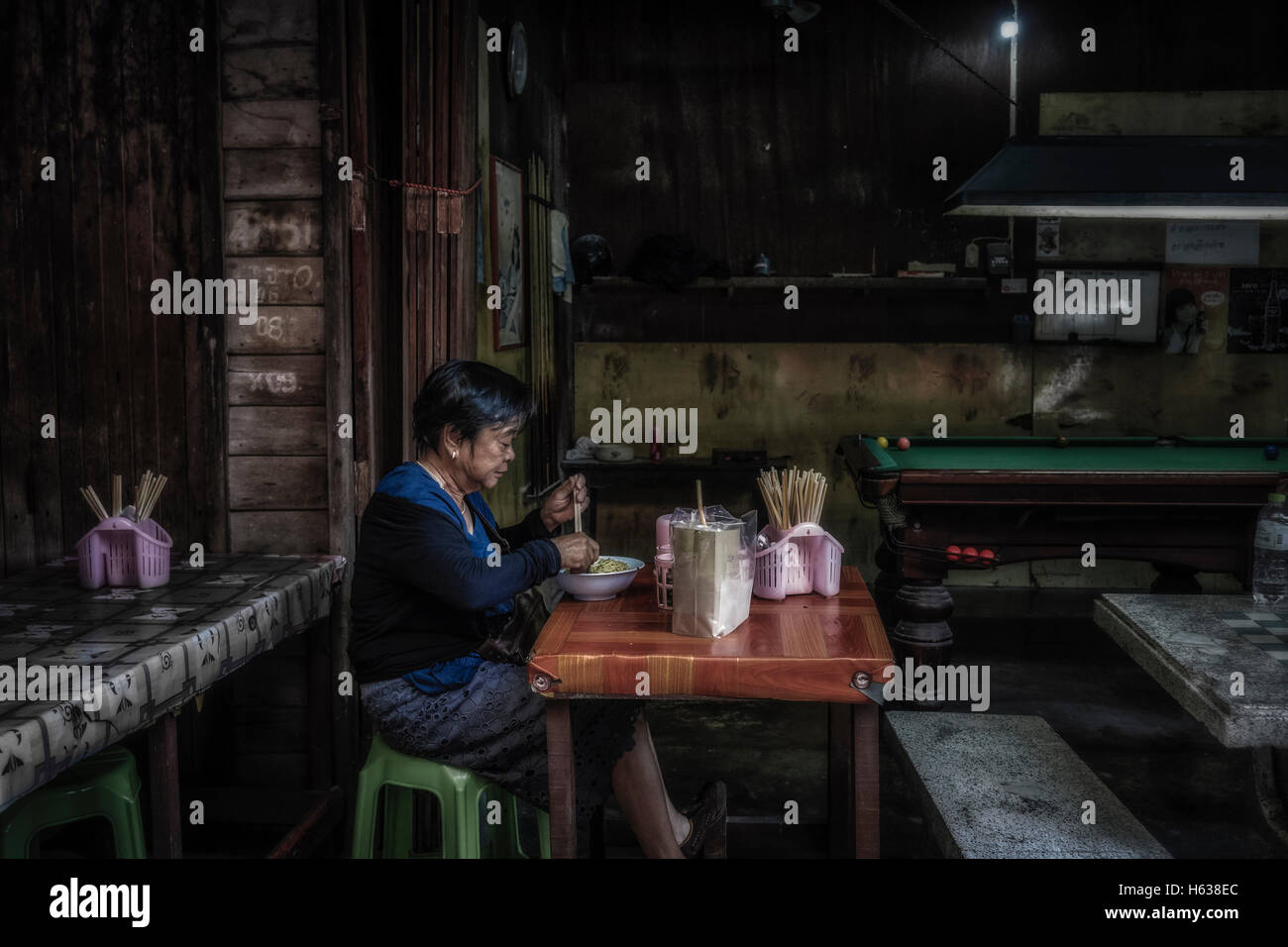 Woman alone restaurant. Woman eating alone in a dingy backstreet restaurant. Thailand S. E. Asia