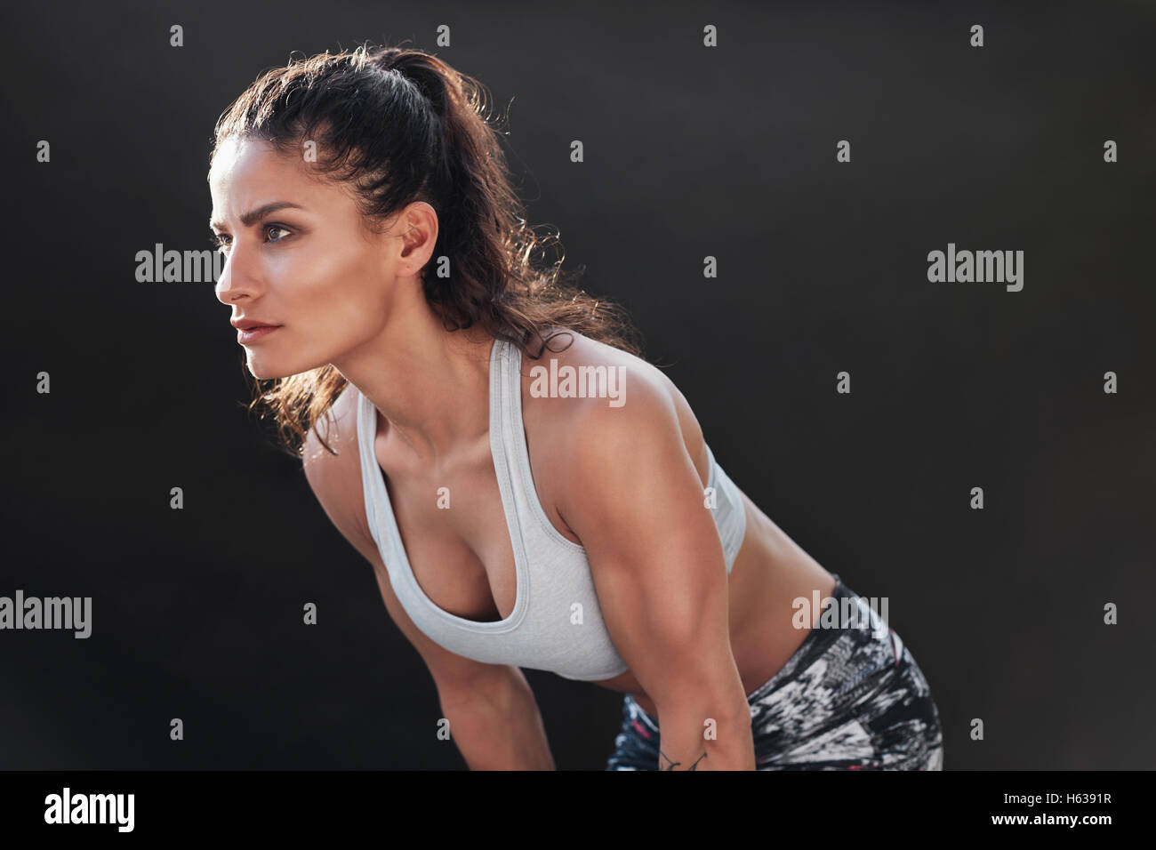 Shot of a strong woman with muscular body in sportswear. fitness female model posing on black background. Stock Photo