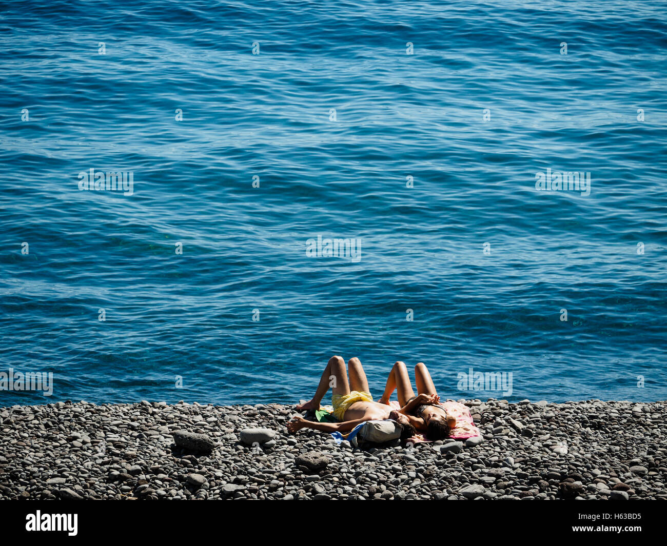 A young couple enjoys the summer at the beach of Faja dos Padres on the Portuguese island of Madeira Stock Photo
